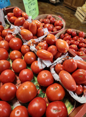 Fresh tomatoes on display at a market with price tags, fresh produce.