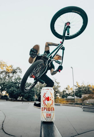 biker popping a wheelie with a spider energy drink can on the concrete