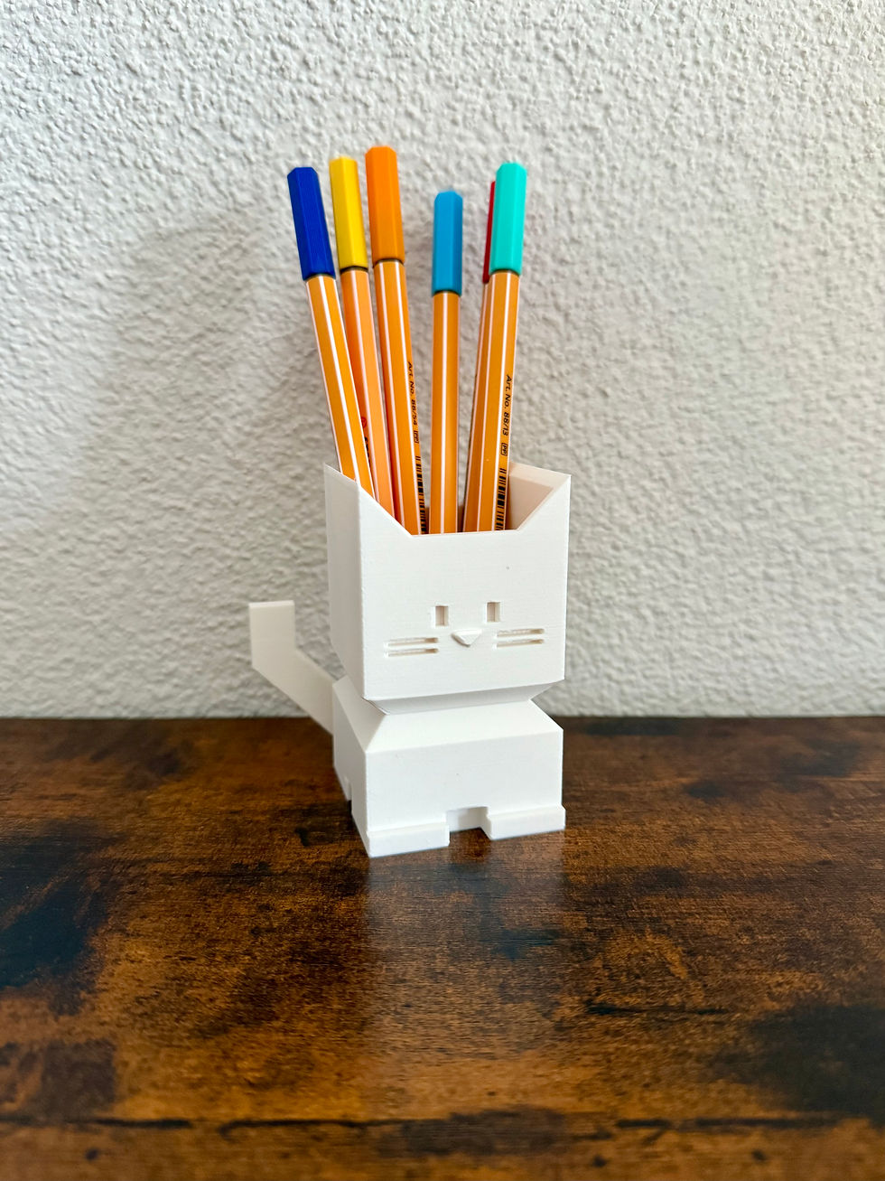 Miniaturbild: Weißer Katzen-Stifthalter mit bunten Stiften, steht auf Holzoberfläche.