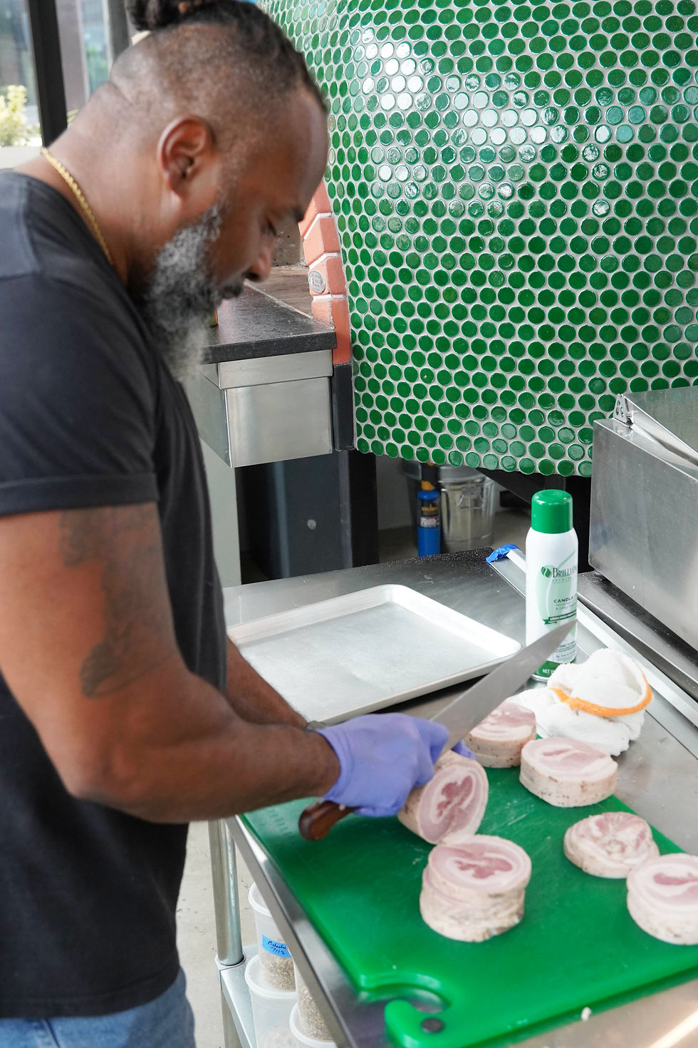 Executive Chef Roderick Nelson slices meat for one of Coastal Crust’s specialty pizzas in the restaurant’s open-air kitchen. JavarJuarez©2026