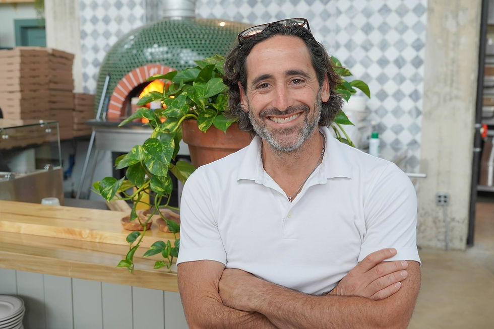 Coastal Crust owner Brian Piesner stands in front of the restaurant’s wood-fired oven. JavarJuarez©2026