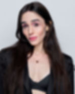 Darwin Del Fabro headshot. She has long brown hair, strong eyebrows and cheekbones, and wears an oversized blazer over a black bra.
