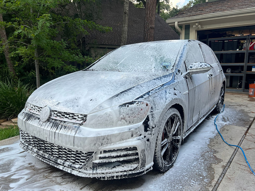 Eye-level view of a shiny black car being washed at a service station