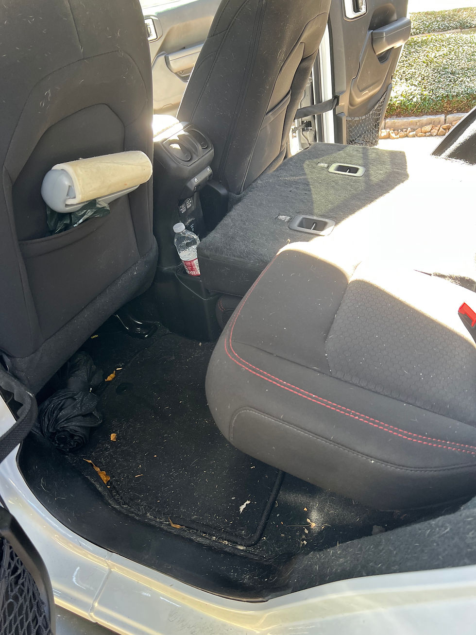 Back seat interior before detailing in Brazoria County TX showing dirt, debris, and buildup on floor