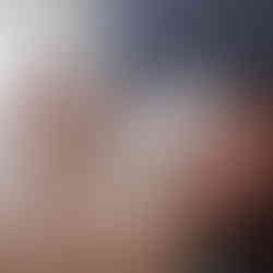 Sioux City pet sitter laying in bed with a doodle licking her face and another sleeping next to her head.