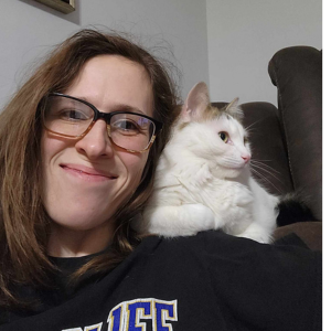 A white cat sitting on DB Pet Sitter's shoulder in owner's home.