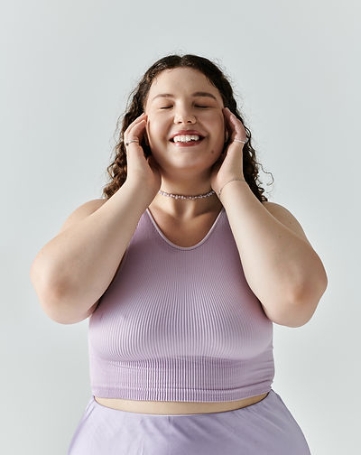 Confident woman in a lavender outfit smiling with her eyes closed—reflecting the joy and empowerment clients experience with