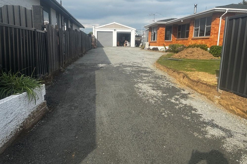 Crushed gravel basecourse spread and leveled along a narrow residential driveway.