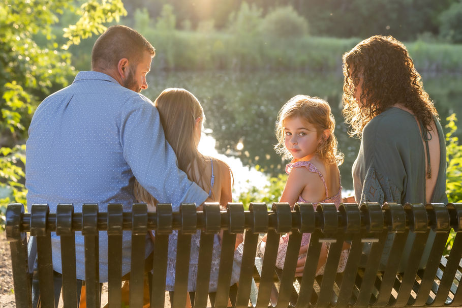 Family sitting on a bench with daughter looking back