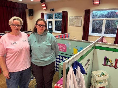 Little city owner stood in front of role play area with launderette and doctors behind 