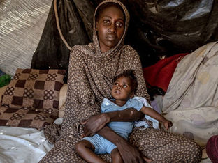 A woman who fled fighting in El Fasher, holds her daughter who was recently treated for malnutrition