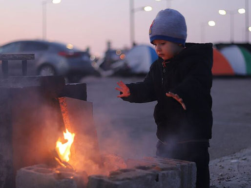 A young child warms himself over a small fire in a Beirut parking lot hosting displaced families from southern Lebanon and other parts of the country
