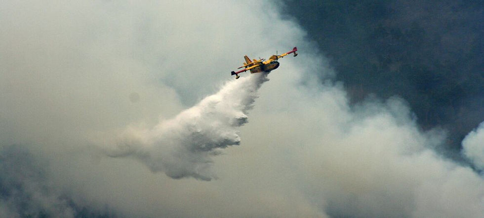 A firefighting plane releases water on a forest fire.