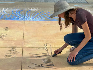 Kamilla signs the interactive chalk mural of the declaration of independence she illustrated as a public art project.