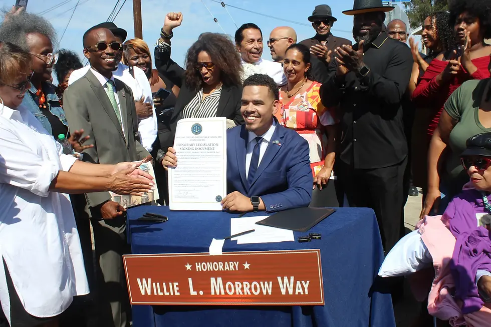 Photo: San Diego Public Advocate Shane Harris signs new city ordinance passed by the San Diego City Council last month into effect at the street sign unveiling ceremony minutes before unveiling the official street sign. Cheryl Morrow daughter of Willie Morrow holds up fist next to Harris.
