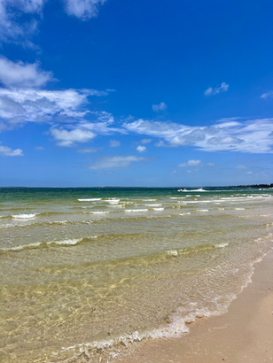 Gentle small waves and clear water at Kyeemagh Beach, against a backdrop of bright blue skies.