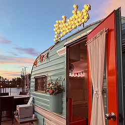 A vintage trailer with a lit up sign on top of it that says, "Photos"