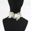 Thumbnail: Wide white lace choker with pink and white ribbon rosettes, as well as white faux fur balls on black mannequin neck.