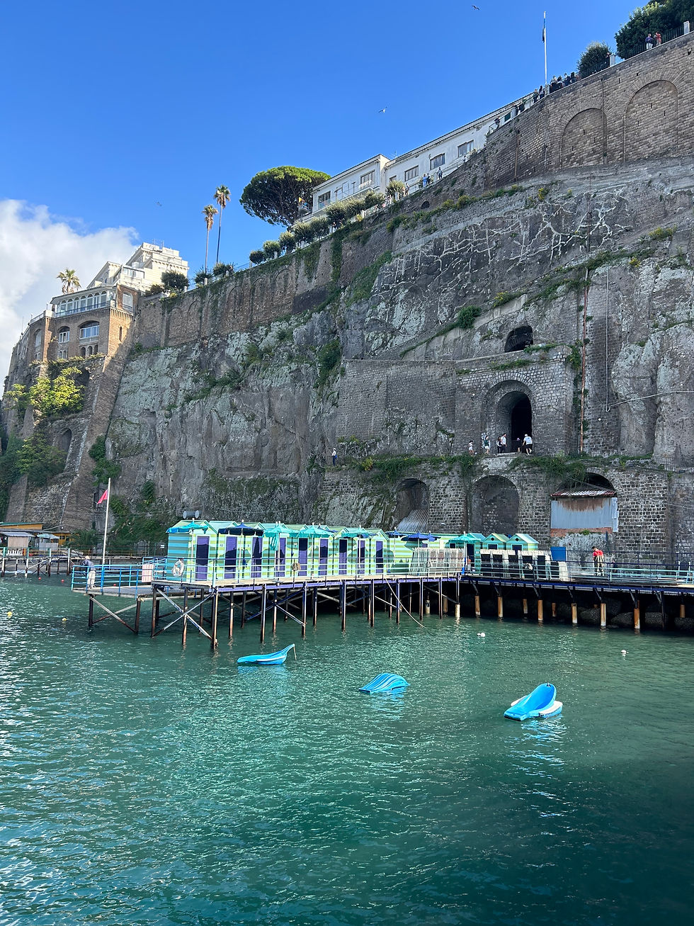 Cliff scenery from a docked beach with blue striped beach huts