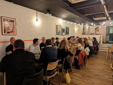 A long table with colleagues sat together eating pizzas