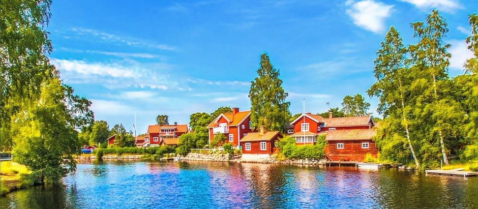 Perinteisiä punaisia puutaloja veden äärellä Taalainmaalla Ruotsissa.
