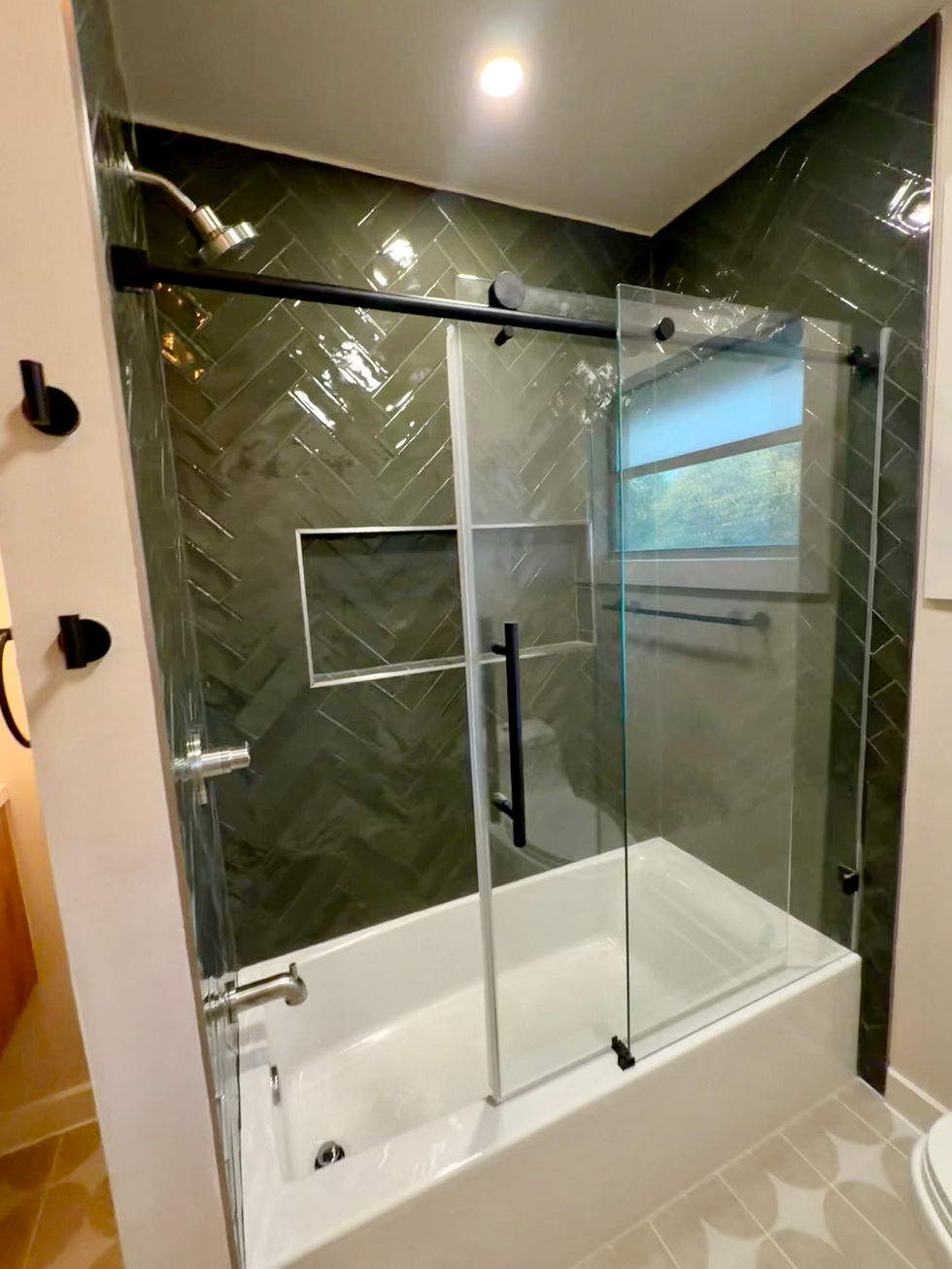White bathtub with dark herringbone wall tile, a rectangular niche, and sliding glass doors.