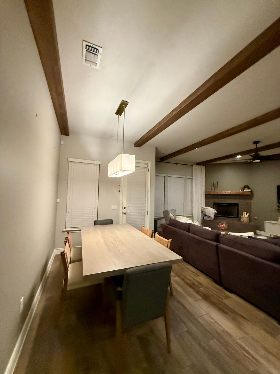 Living and dining room featuring custom-installed ceiling beams and a new pendant light fixture; SMTX Contractors removed two recessed lights to improve the lighting layout and enhance architectural detail.