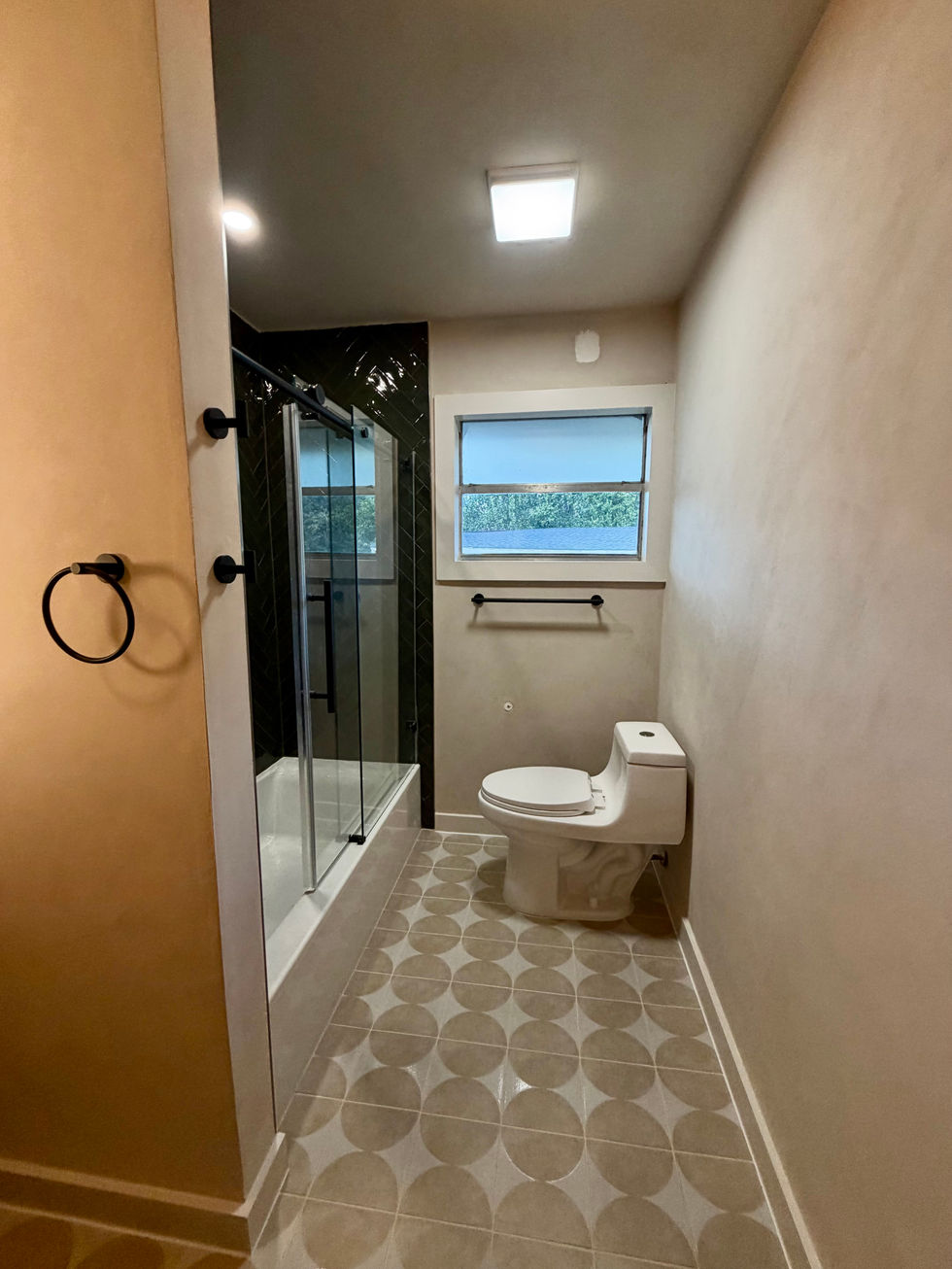 Doorway view of patterned bathroom flooring, textured walls, and a toilet at the far end.