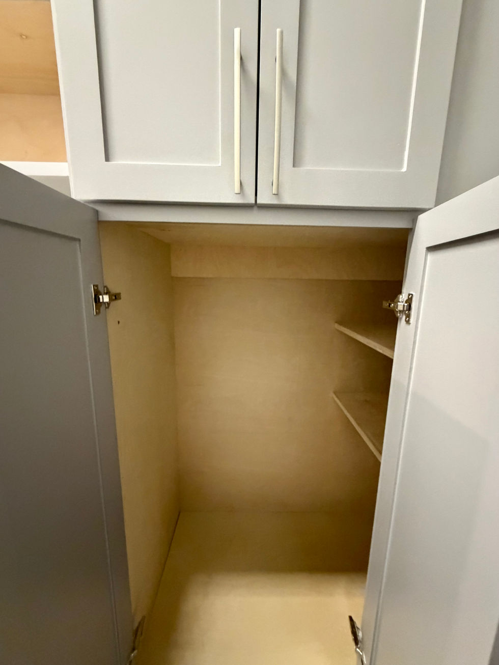 Custom cabinet with painted doors, long metal handles, and an open lower storage compartment.