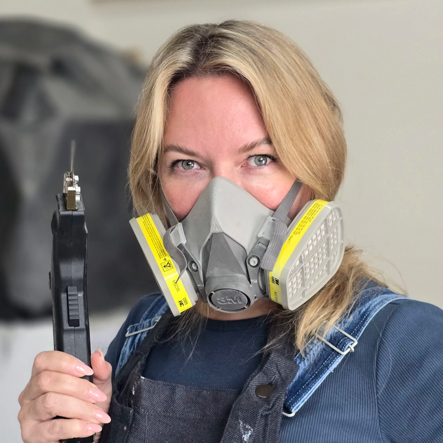 Artist wearing respirator mask, holding tool