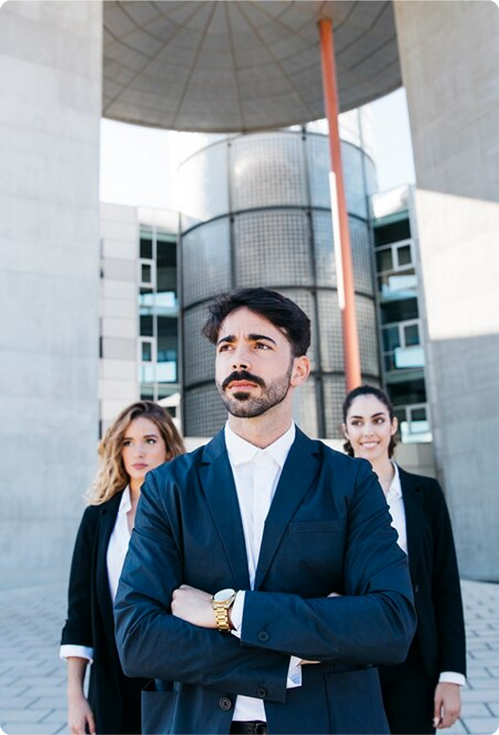 Confident businessman with colleagues, arms crossed, modern building background