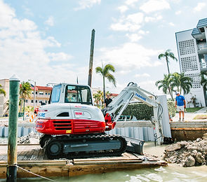 Excavator installaing sheet panels for seawall.