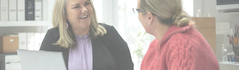 Daina and a person sitting at a laptop having a meeting and smiling