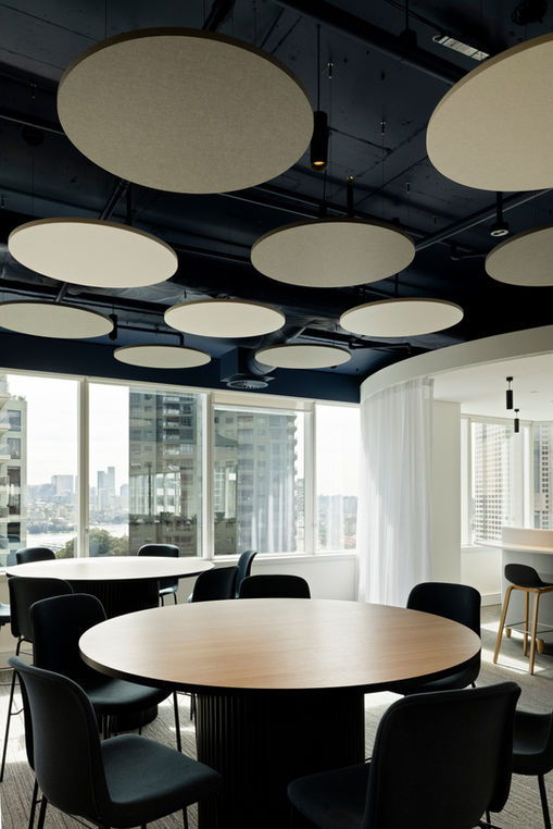 Modern Sydney office interior with round meeting tables, acoustic ceiling panels and city skyline views, captured by Bruce Robinson Photography specialising in design and architecture photography Sydney and commercial interior photography.