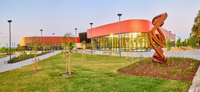 Modern campus courtyard with trees, paved walkways, and a red building, with a person skating through the foreground at dusk.
Landscaped public plaza with trees, seating, and paved paths leading to a modern red building, with a blurred skateboarder moving through the foreground at dusk.
Evening view of a modern landscaped campus with pathways, trees, and a red building.
A contemporary landscaped campus featuring paved walkways, trees, seating, and steps, leading to a modern red building with large windows, while a skateboarder passes through the foreground at dusk.