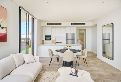 Bright, open-plan apartment interior featuring a modern white kitchen, dining area, and living space with neutral furnishings, natural light, and contemporary finishes, highlighting stylish apartment living, functional design, and high-quality residential interiors.
