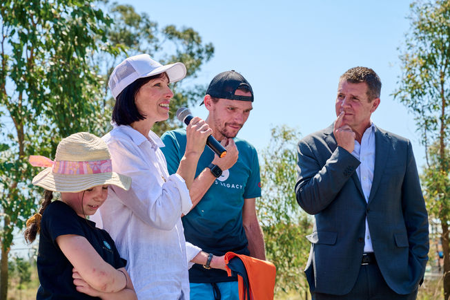 runners shoes people speakers green shorts green shirts blue sky road flags microphone