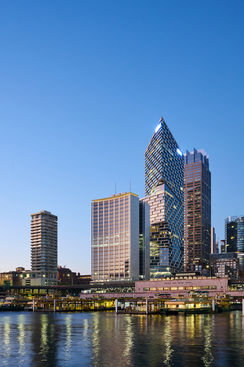 City skyline at dusk reflected on a river, with illuminated modern buildings along the waterfront. Modern city skyline at dusk with illuminated high-rise buildings along a waterfront, reflected in calm river water. A contemporary city skyline at dusk featuring distinctive high-rise buildings along a waterfront, with lights reflecting across the river under a clear blue sky.Evening city skyline with waterfront reflections. Sydney Circular Quay at dusk with the AMP Building, one of Sydney’s first skyscrapers, standing along the waterfront and reflected in the harbour. Sydney Circular Quay skyline at dusk, featuring the historic AMP Building reflected on the harbour.
The Sydney Circular Quay skyline at dusk, highlighting the AMP Building—one of the city’s earliest skyscrapers—alongside contemporary towers, reflected in the harbour waters.Sydney Circular Quay at dusk, featuring the AMP Building, one of Sydney’s first skyscrapers, set against the modern city skyline and harbour reflections.