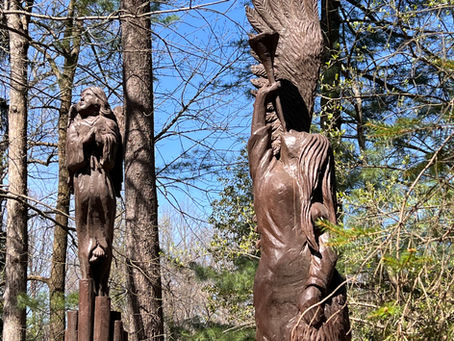 Two wood carvings in a sunny forest setting