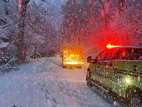 Several emergency vehicles at dusk during snowy weather.