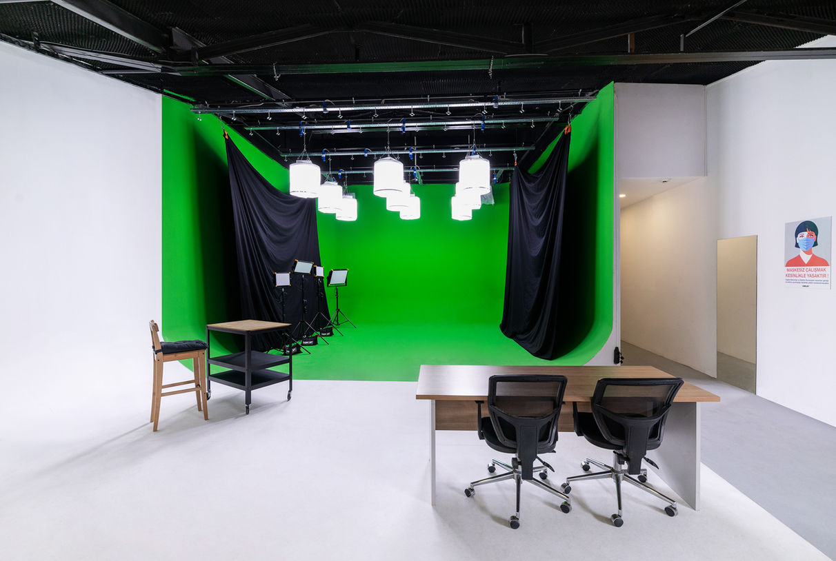 şık kontrolü sağlamak amacıyla siyah perdelerle desteklenmiş yeşil fonlu stüdyo.