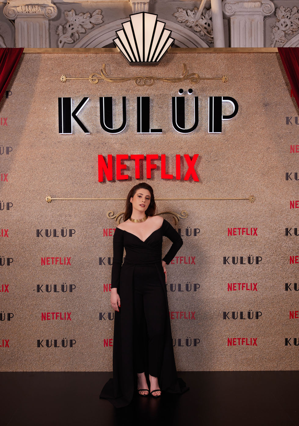 Oyuncu Asude Kalebek Netflix Kulüp lansman gecesinde kırmızı halıda objektiflere gülümsüyor.