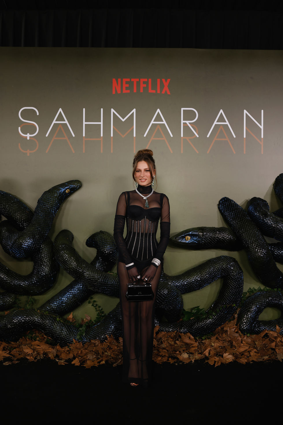Serenay Sarıkaya, Netflix Şahmaran lansmanında logolu kırmızı halı basın panosu önünde poz verirken Novart İstanbul imzalı kurumsal PR fotoğrafı.