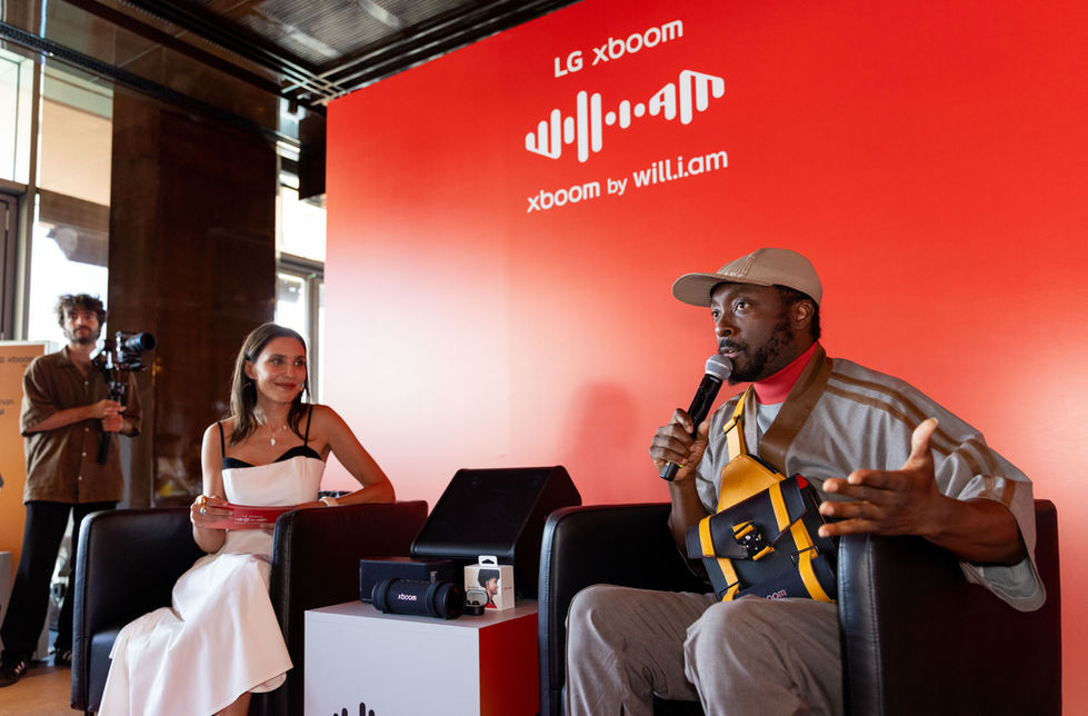 LG XBOOM lansman etkinliğinde sahnede oturarak soruları yanıtlayan marka yüzü will.i.am ve sunucunun röportaj anı.