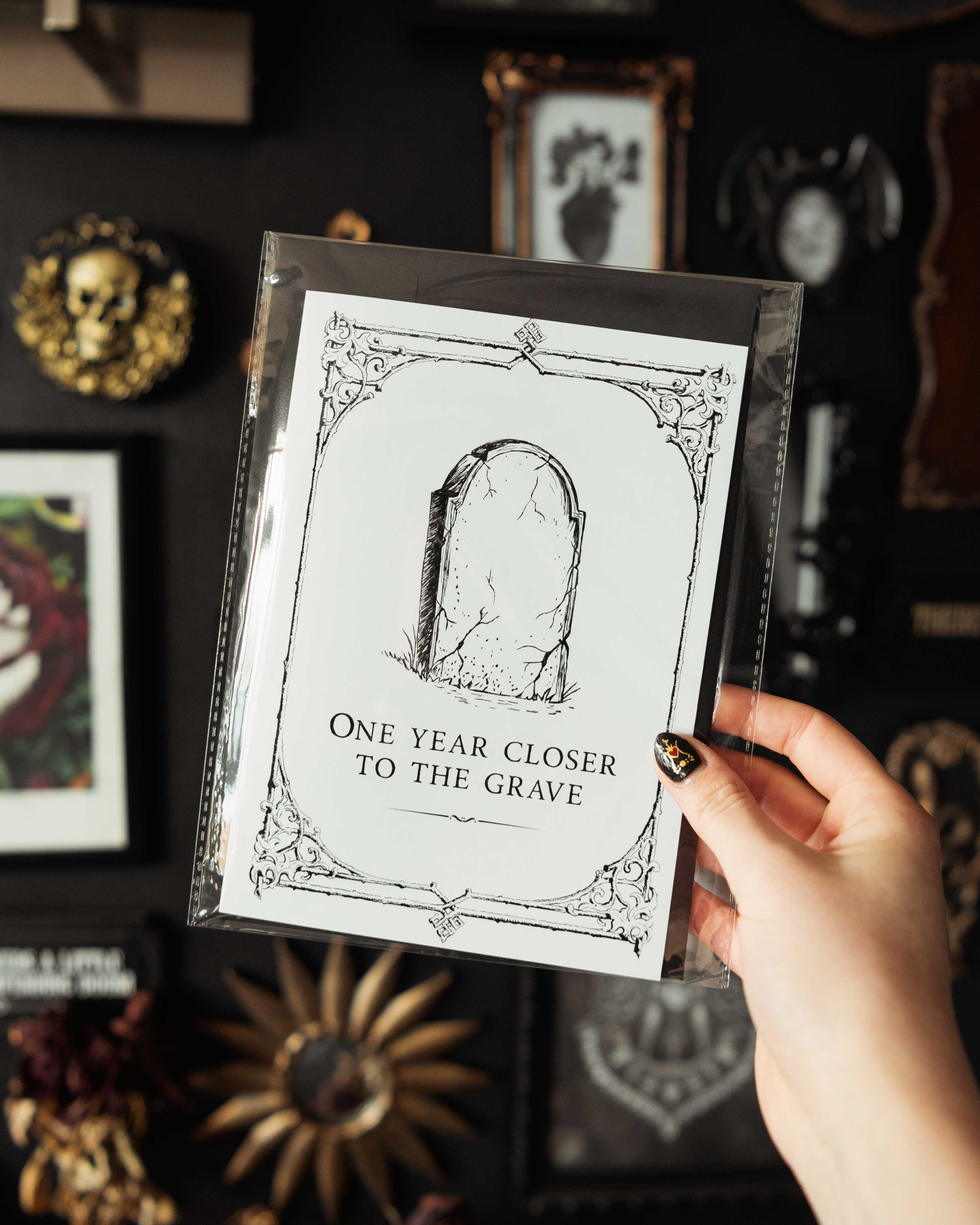 A5 gothic birthday card with a light grey background, vintage ornate border, an illustration of a headstone and text.