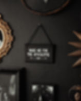 Black, gothic wall sign with the phrase "Wake Me for the Apocalypse," in white, hanging on a dark wall