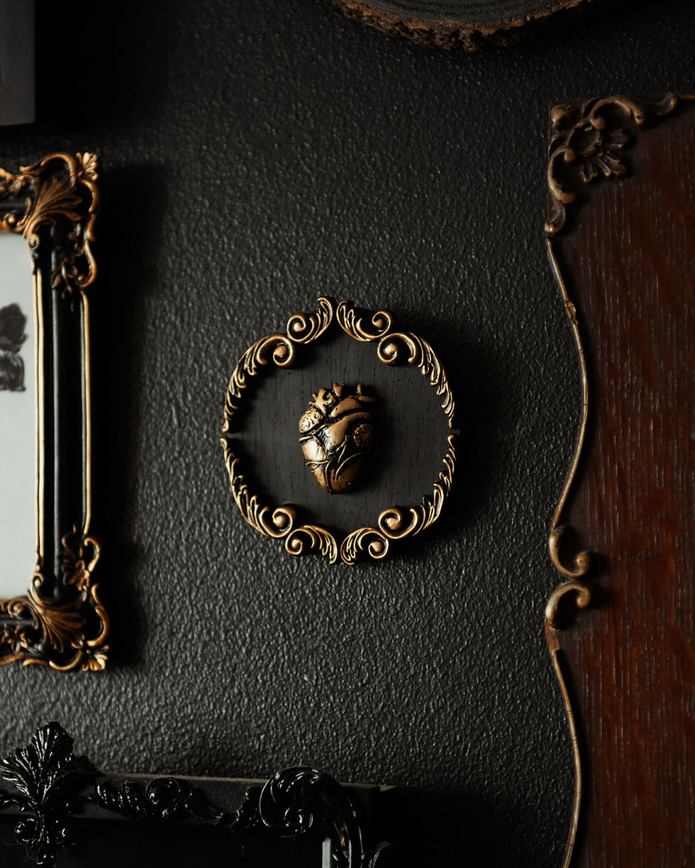 A detailed gothic wall hanging featuring a sculpture of a human heart, framed within an ornate circular border.