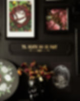Long black sign with gold text in a gothic font that says Til Death Do Us Part. Hanging on a goth maximalist gallery wall