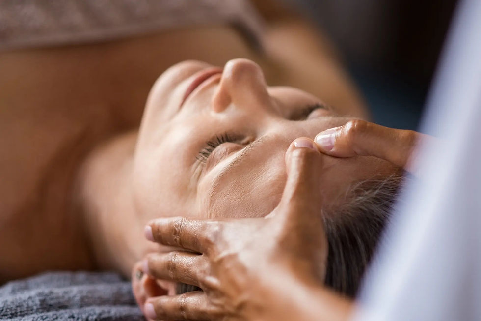 Person receiving a forehead massage with eyes closed, set against a soft background. The scene conveys relaxation and calmness.