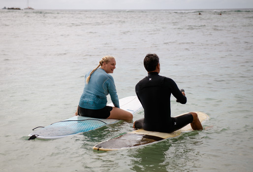 surf teacher and student talking and waiting for a wave